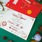 Personalised Nice List Certificate and Red Envelope with gold foil text and golden reindeer seal. Printed on smooth ivory card stock and foiled in a stunning red and gold, each certificate is personalised to the child. The certificate reads: "Santa's Official Nice List Declaration. This is to certify that [child's name here] has been placed on the official Christmas Nice List of 2022 for being jolly good this year! Keep up the good work!" Signed by Santa Claus and checked twice.